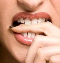 Frau beißt auf Finger Zähneknirschen