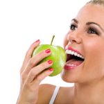 Frau beißt lächelnd in Apfel