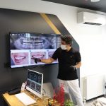 11Dentist examining full mouth dental implant treatment on screen