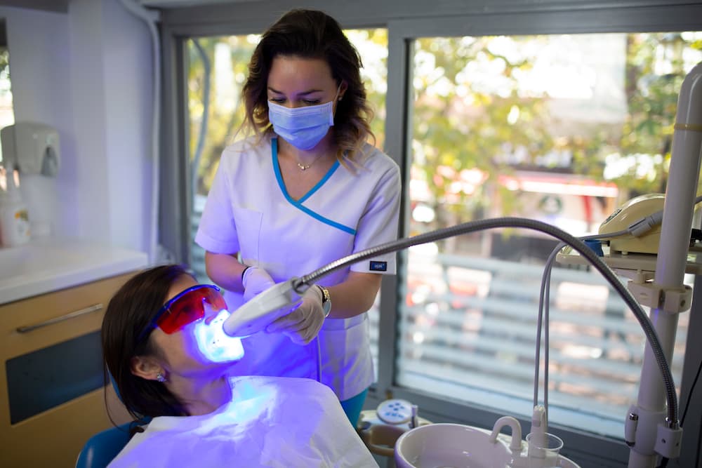 woman whitening teeth with dental laser
